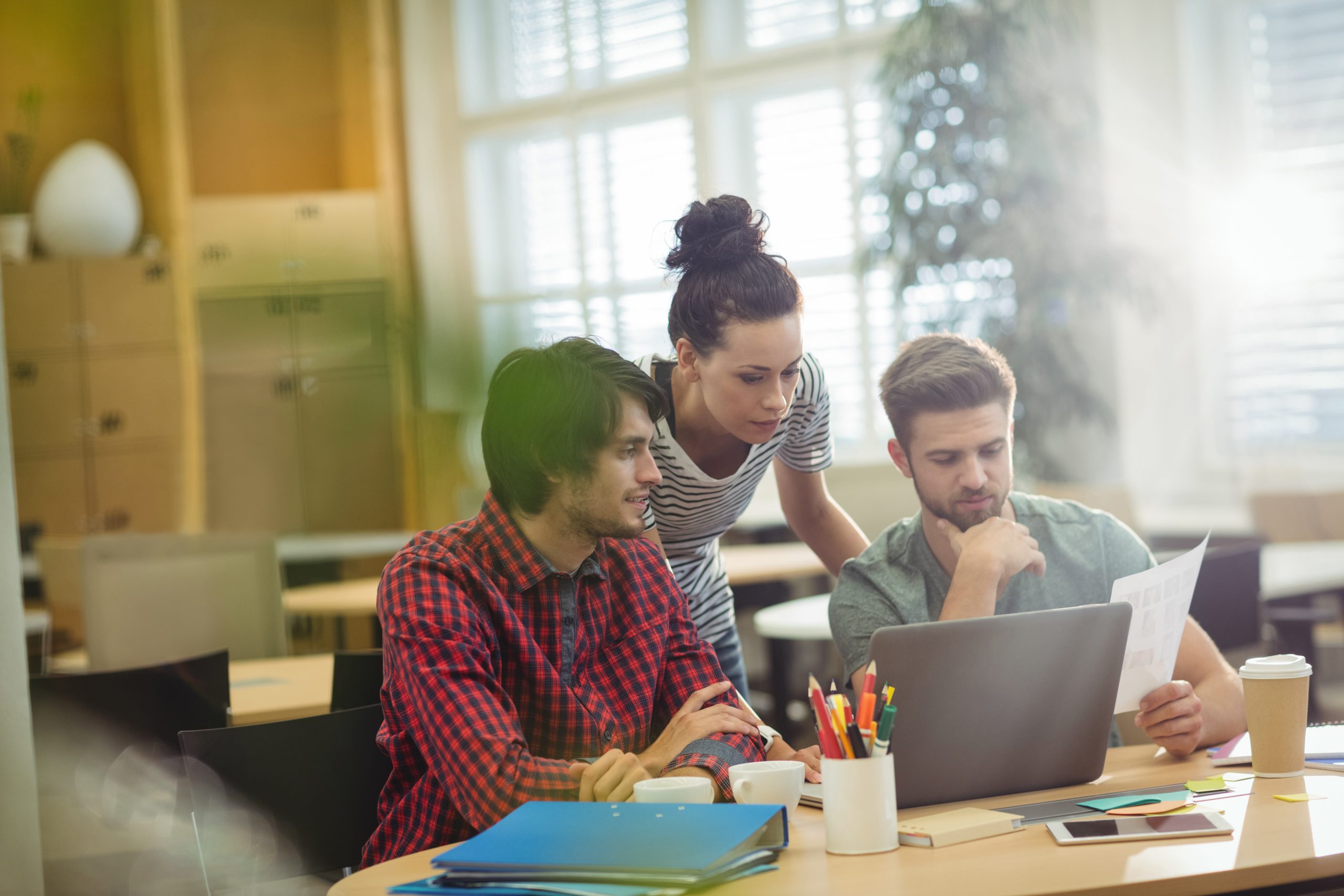 Group of business executives discussing over laptop at their desk
